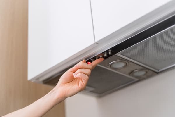 A person pressing a button on a recirculating kitchen fan - iStock Credit: brizmaker
